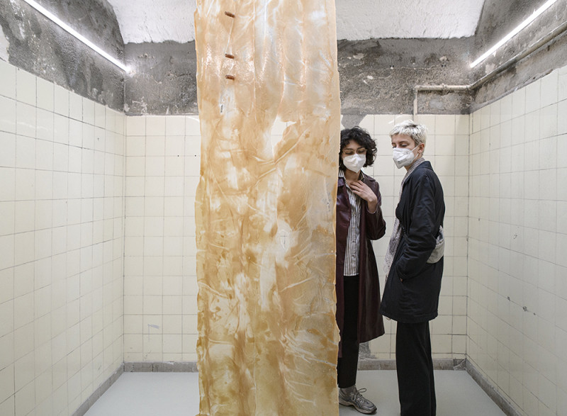 There is an installation in the middle of the room, the visitors look at it.  It looks like a brown, white transparent cloth.