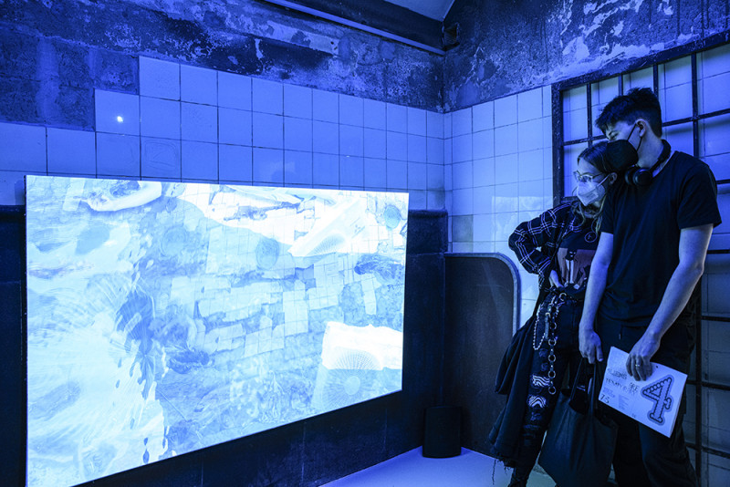 Visitors are watching a videoinstallation.