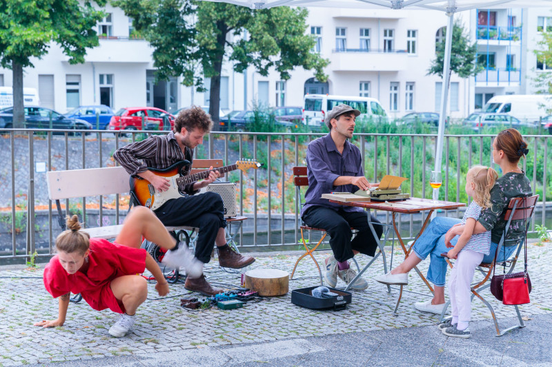 Life Performance. Die Künstler tanzen, spielen Gitarre und interagieren mit Besuchern.